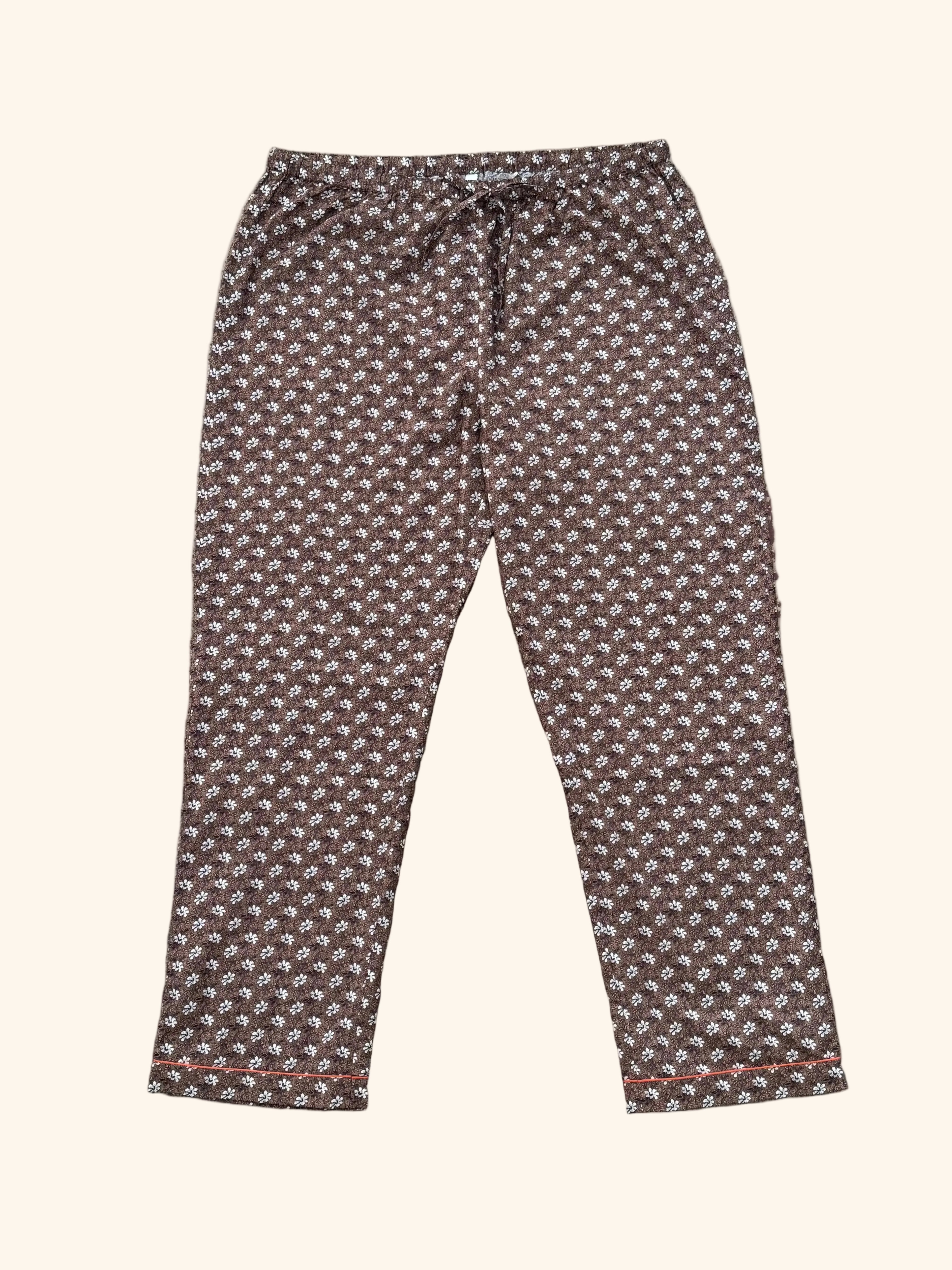 A pair of cropped pants with a brown, white, and red geometric pattern, laid flat on a distressed concrete floor.