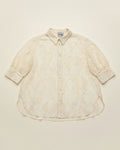 An off-white textured button-up shirt with short puff sleeves, laid flat against a solid cream background.