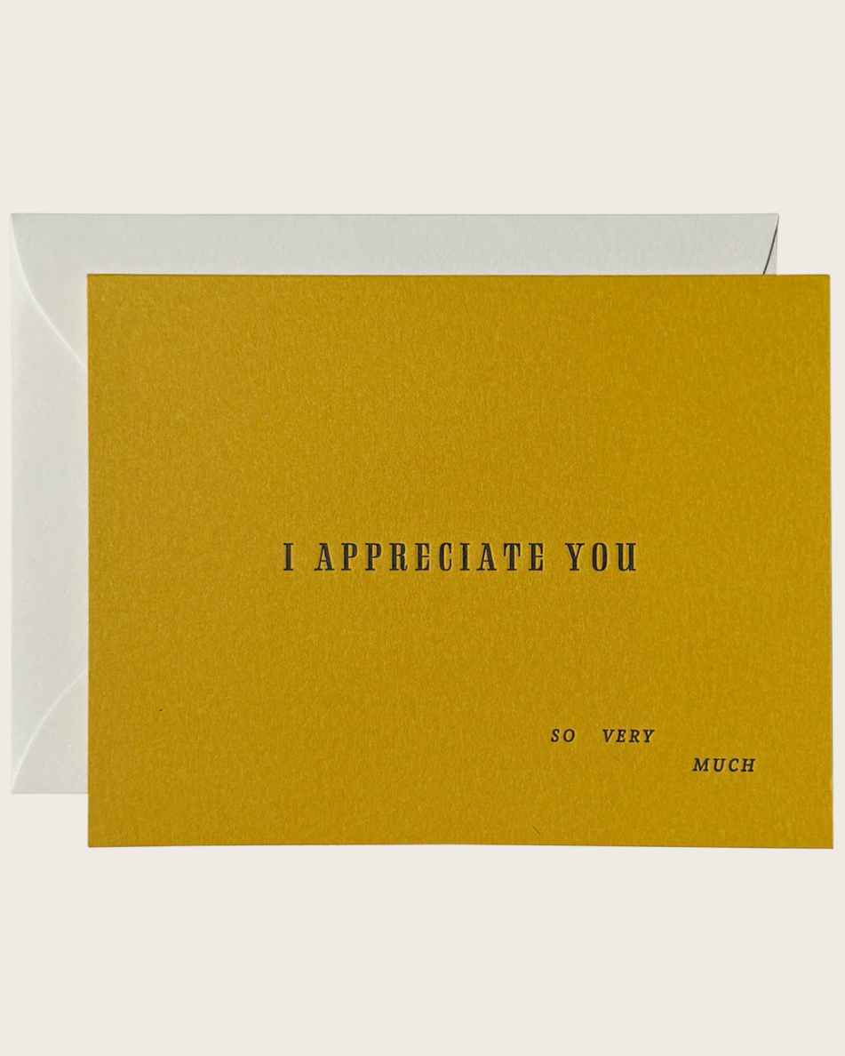 A square yellow greeting card with the text 'I APPRECIATE YOU SO VERY MUCH' printed in black, shown with a white envelope behind it on a light beige background.