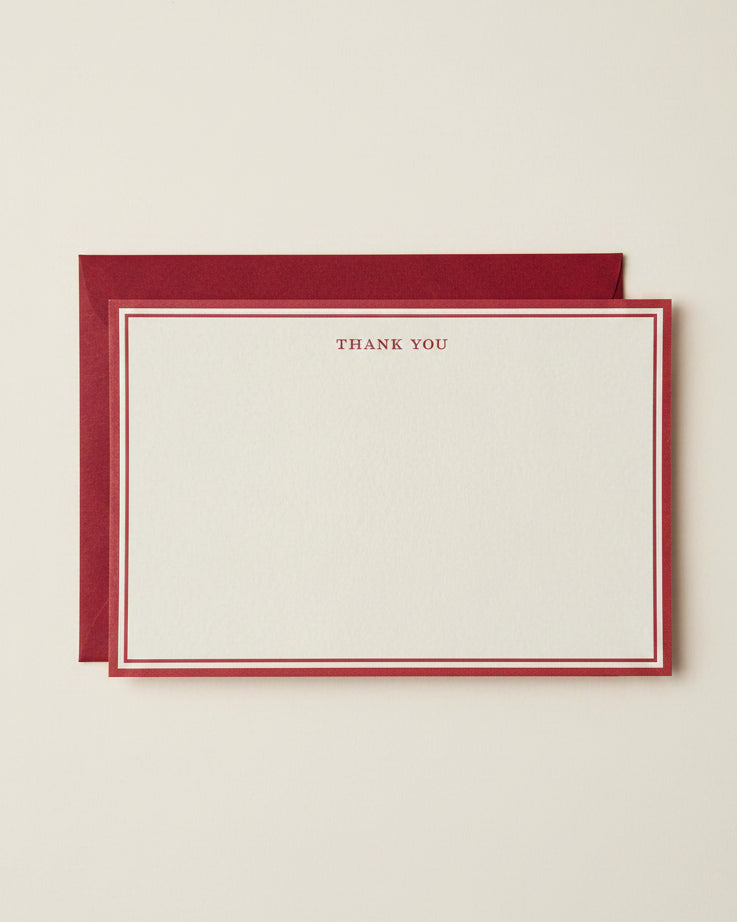 A cream-colored thank you card with a red border and the words 'THANK YOU' printed at the top, shown with a matching red envelope behind it on a white background.